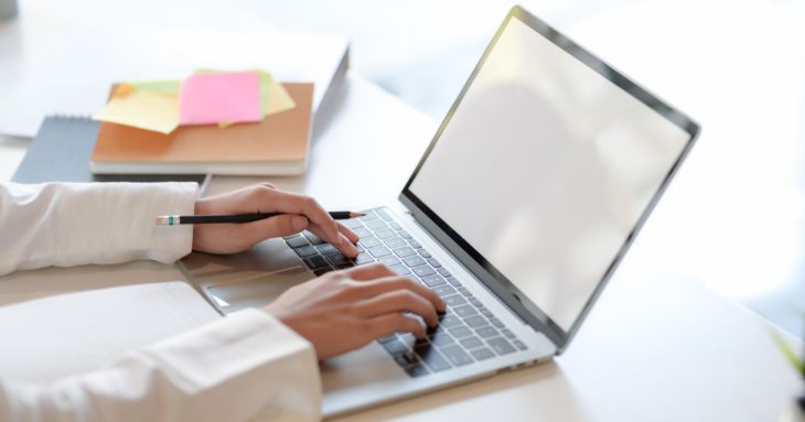 デスクにてデスクトップPCを操作する女性の両手