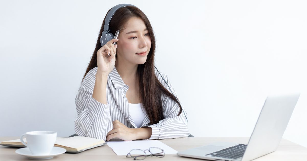 穏やかな表情でパソコンを眺める、ヘッドフォンをした女性