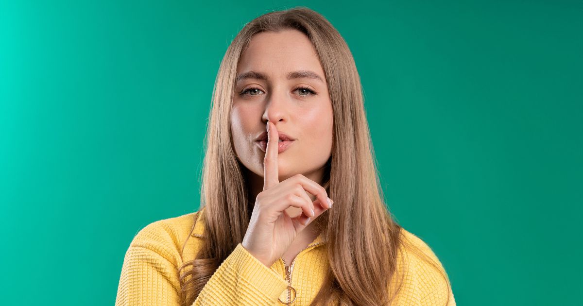 唇に手を当て、静かにするよう求める女性