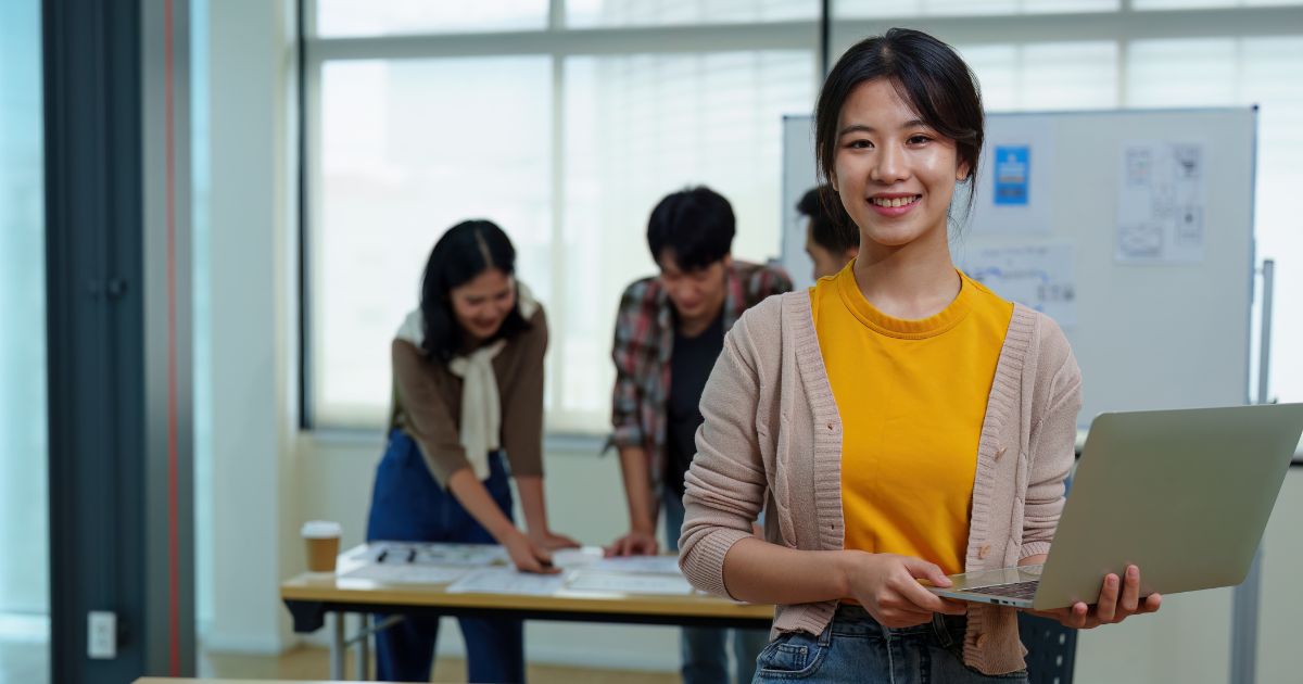 ノートパソコンを手にほほ笑むビジネスパーソン