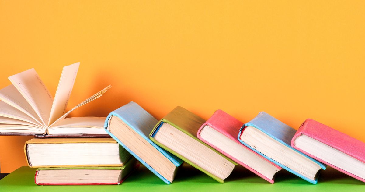 オレンジ色の背景で、カラフルな本が並ぶ様子