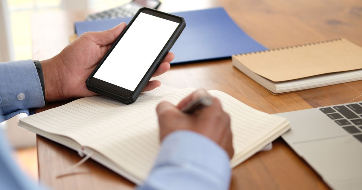 スマートフォンを手にもちメモをとる人の手元