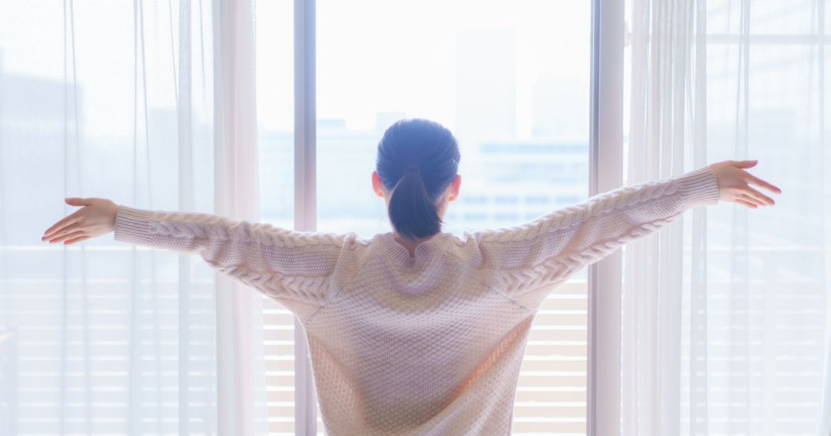 朝の日の光を浴びる女性の後ろ姿