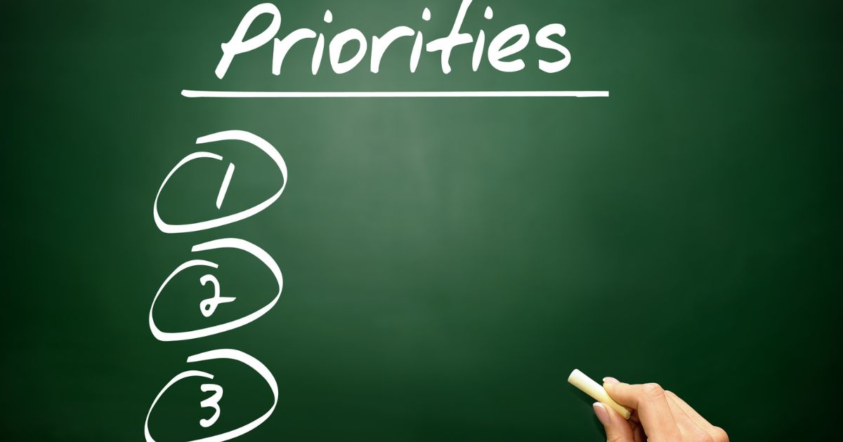 黒板に「Priorities」とチョークで書く様子