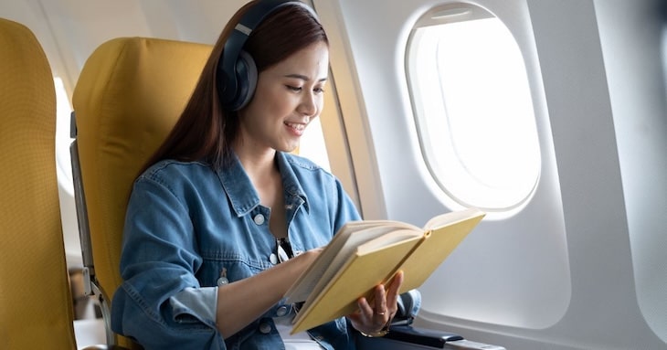 飛行機での移動中に読書をしている様子