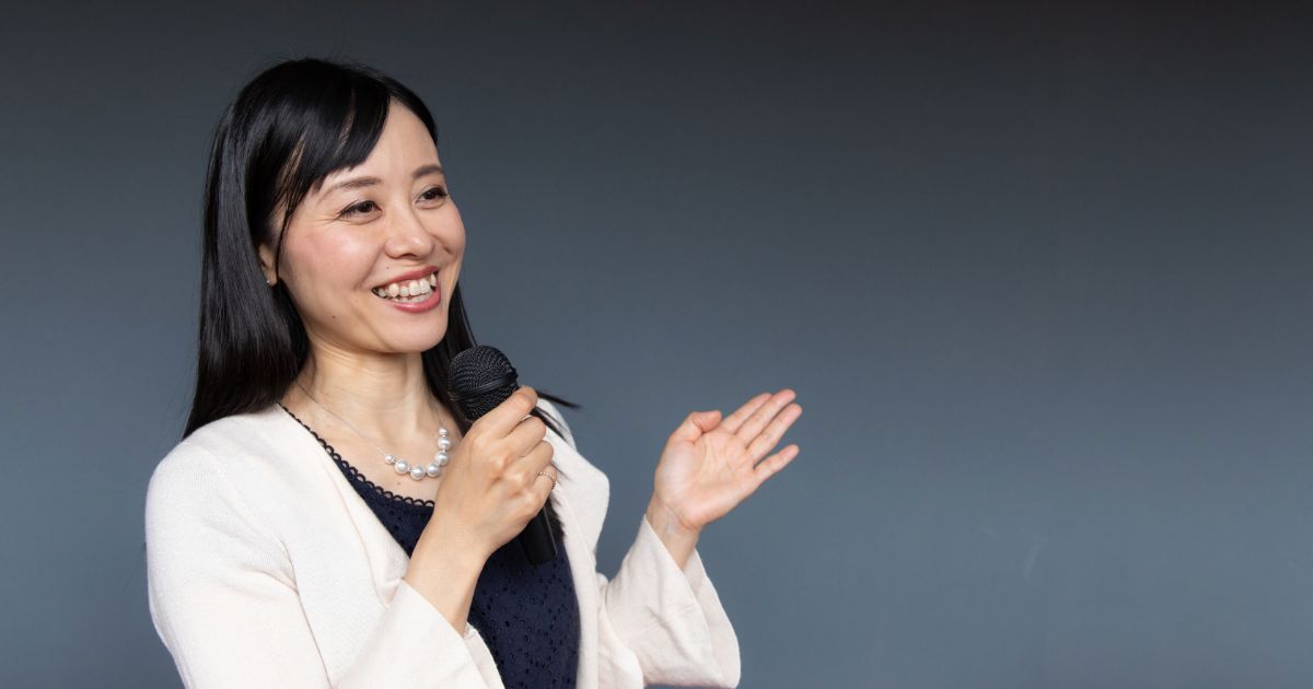 ç½ãã«ã¼ãã£ã¬ã³ã®å¥³æ§ãããã¤ã¯ãæã¡å·¦æã§ã¸ã§ã¹ãã£ã¼ããªããç¬é¡ã§è©±ã