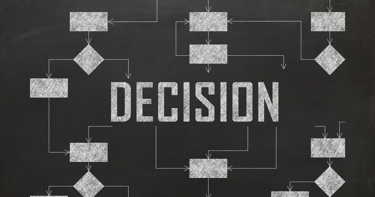 黒板にチョークで描かれたフローチャートと「DECISION（決断）」の文字