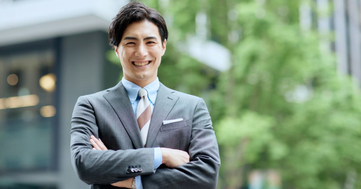 笑顔で腕を組む男性ビジネスパーソン