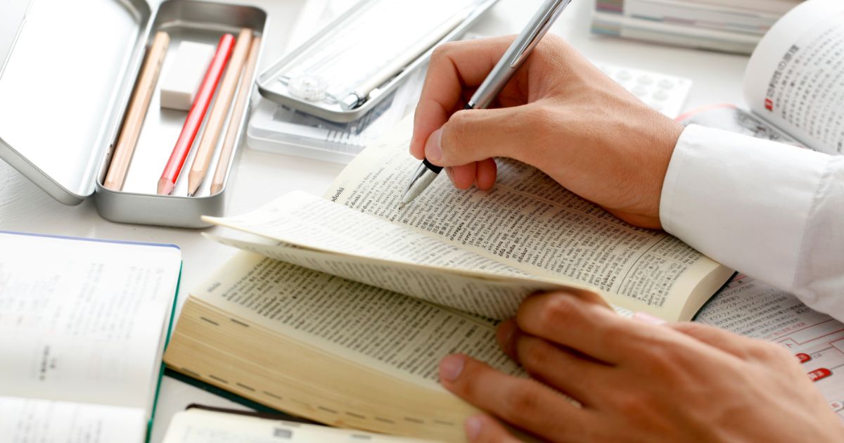 机に広げた辞書に書き込みながら勉強している人の手元