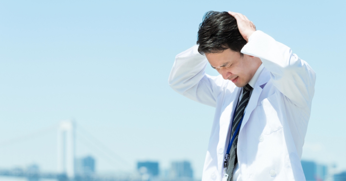 睡眠不足で頭を抱える男性のイメージ。記憶の定着には十分な睡眠が不可欠