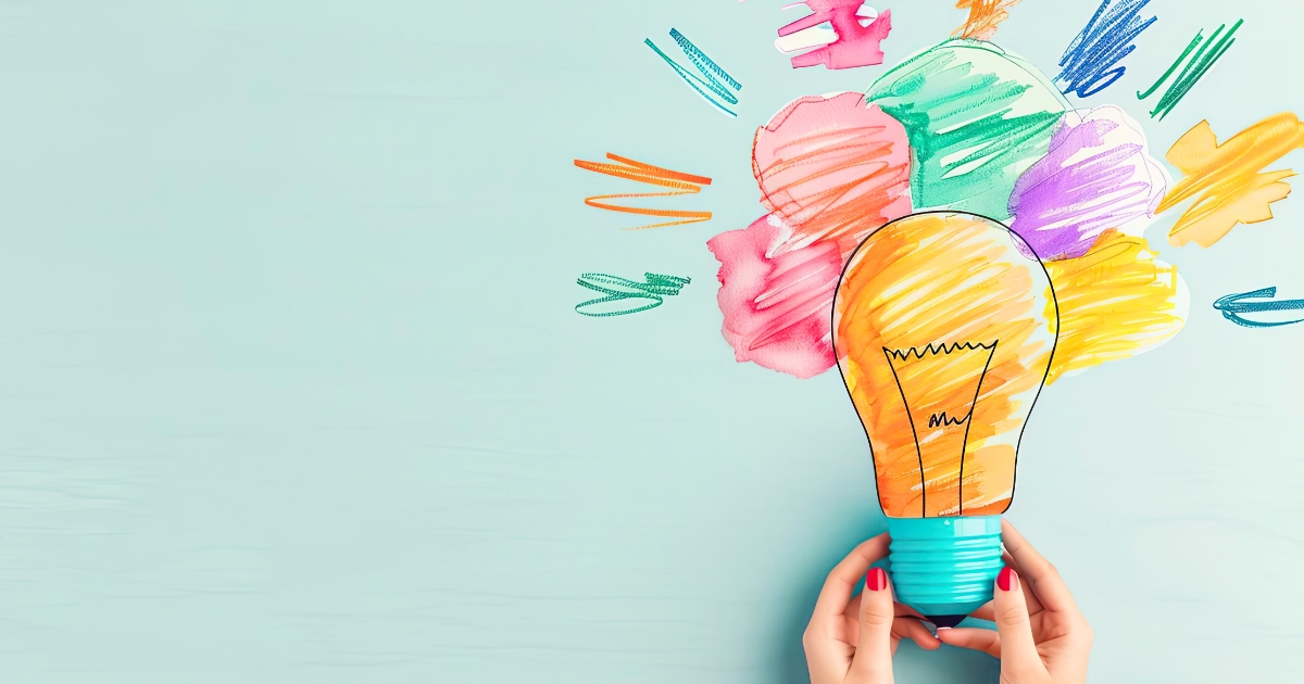 カラフルな絵の具で描かれた電球のイラストを両手で持つ様子