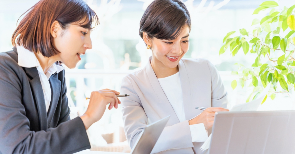 ノートPCを見ながら相談するビジネスパーソン。意思決定や仕事の進め方を話し合う場面