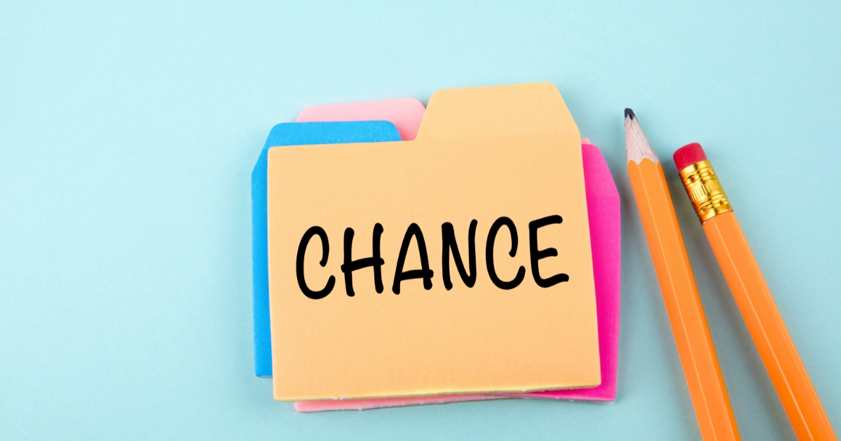 黄色い付箋に「CHANCE」と手書きされ、横に鉛筆が置かれたデスク。アイデア発想のワンシーン