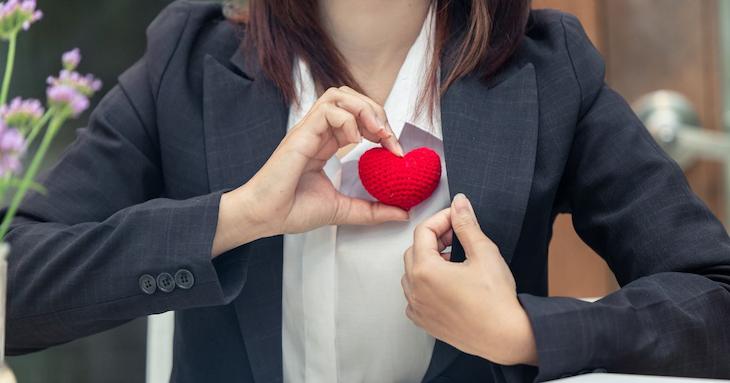 スーツを着た女性が赤いハートのオブジェを持っている