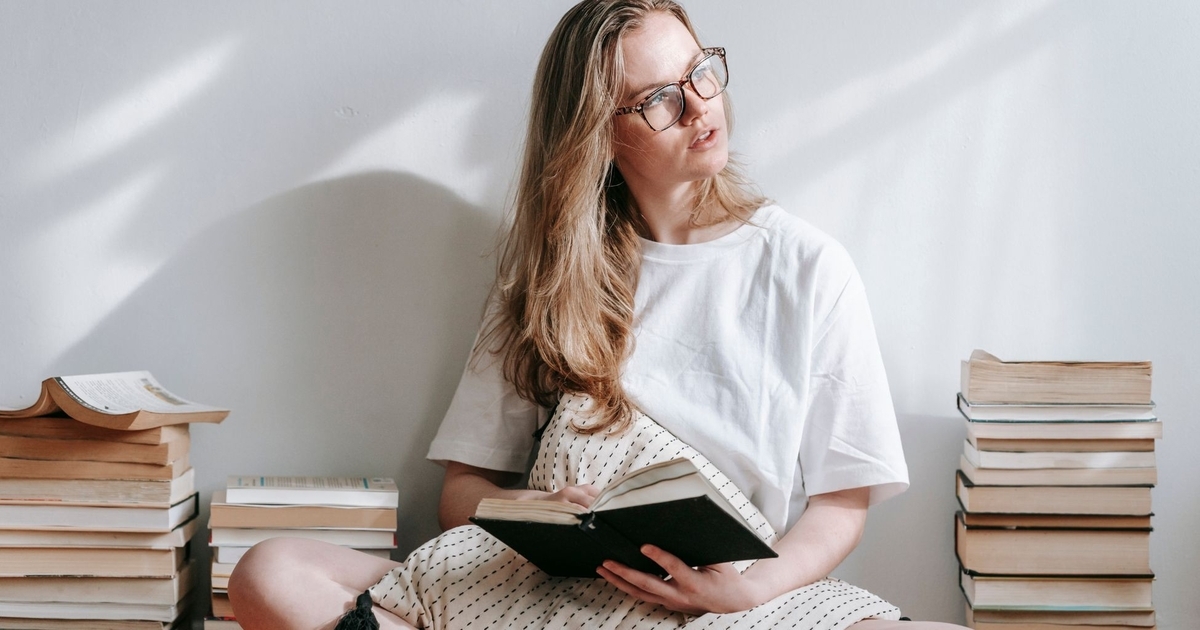 白い壁の前で読書をする女性