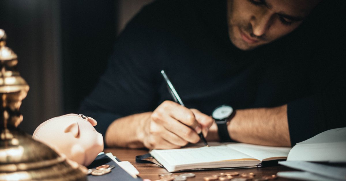 暗い部屋で男性が紙にペンで書き出している