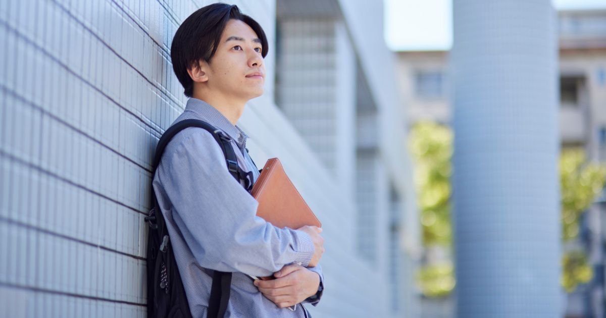 本を持って立つ男性
