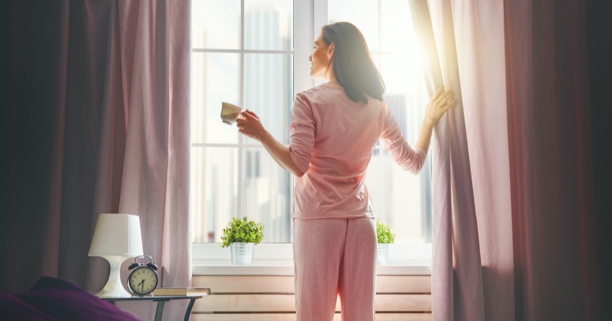 起床してカーテンを開ける女性