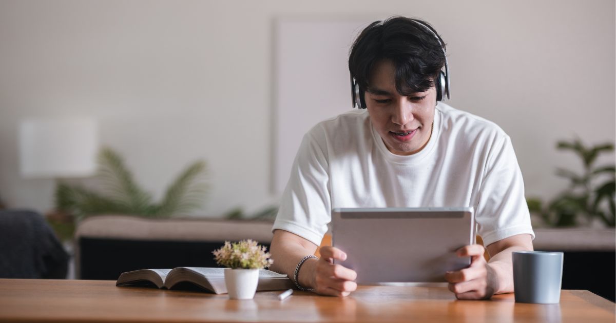 ヘッドホンをつけ、タブレットを手に持っている男性