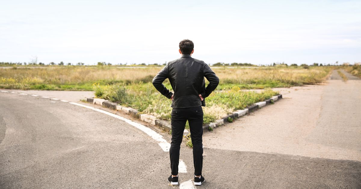分かれ道の前で悩んでいる男性