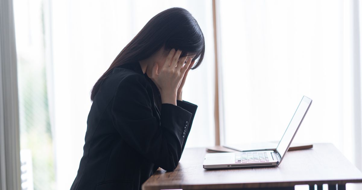 デスクに座って悩んでいる女性