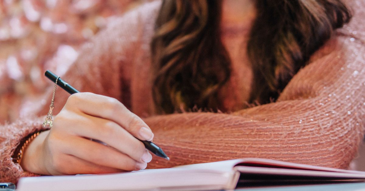 ノートに手書きしている女性