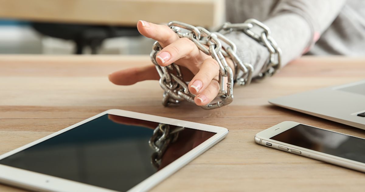 鎖に縛られた人がタブレットに手を伸ばそうとしている