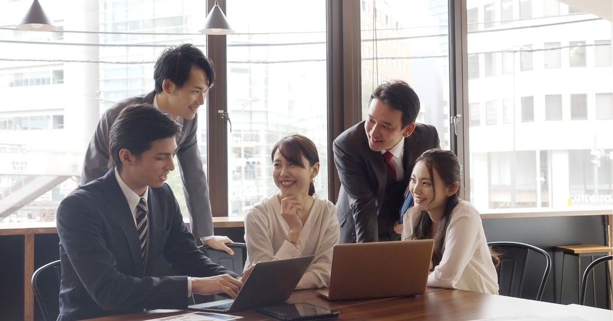 パソコンを囲んで会話している従業員たち