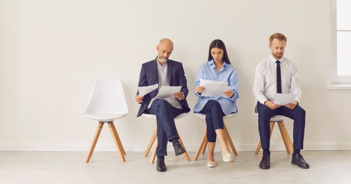 4つのイスに3人のビジネスパーソンが座っている