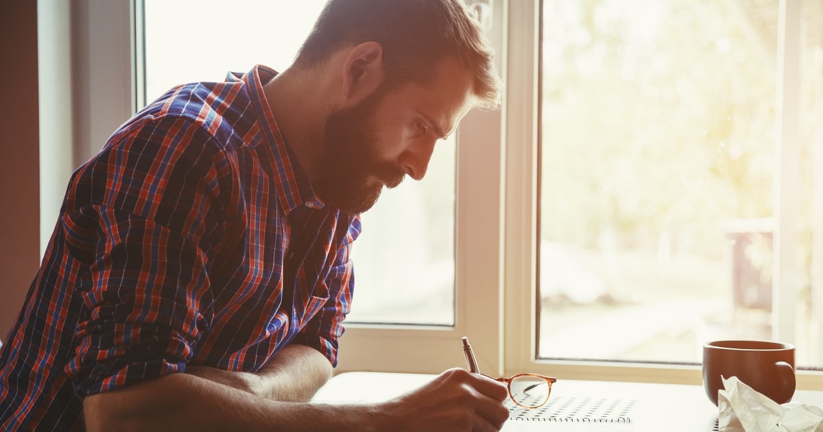イラついたことを紙に書くカジュアルなスタイルのビジネスパーソン