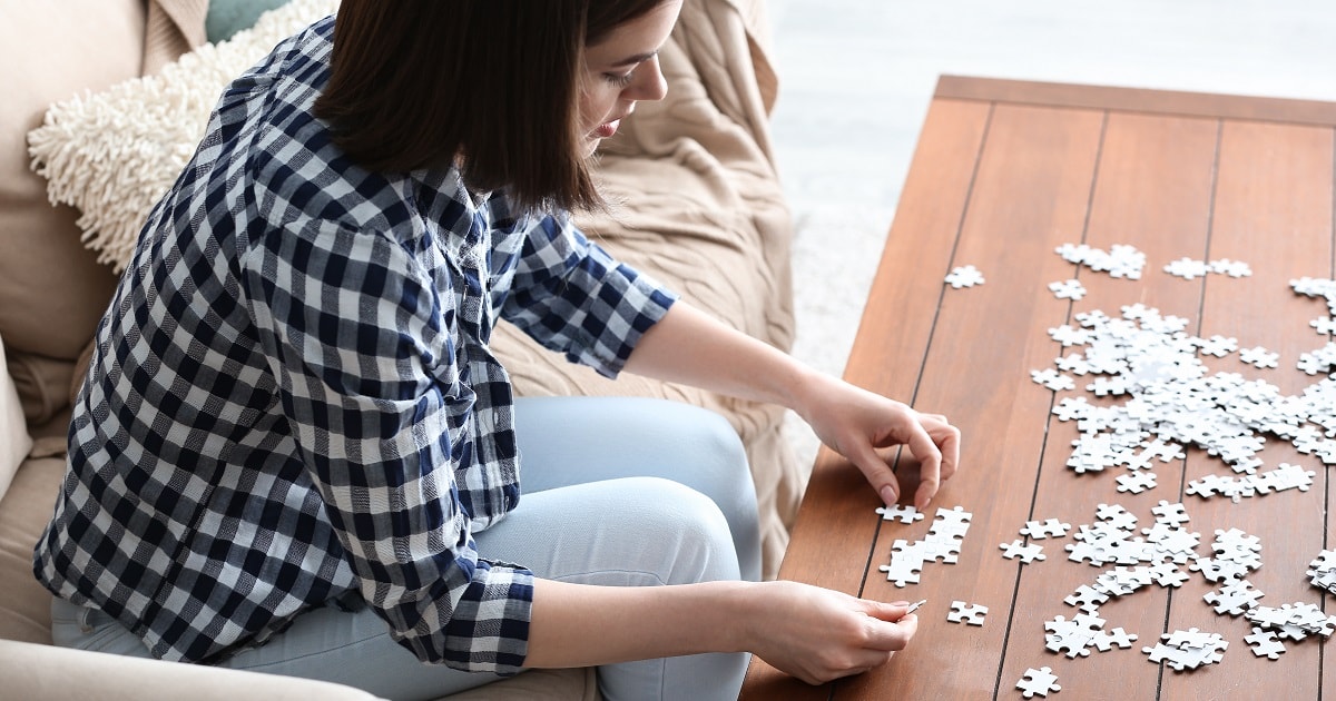 自宅でジグソーパズルを行う若い女性