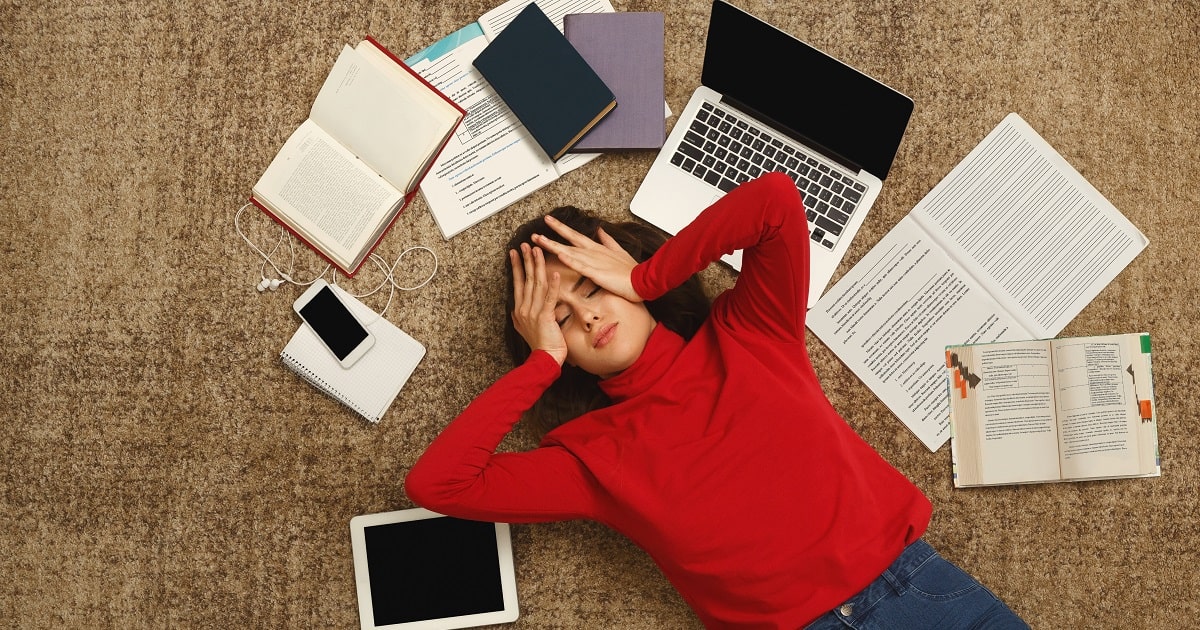 「もうダメだ」と勉強を投げ出したくなっている赤いニットの学生あるいはビジネスパーソン