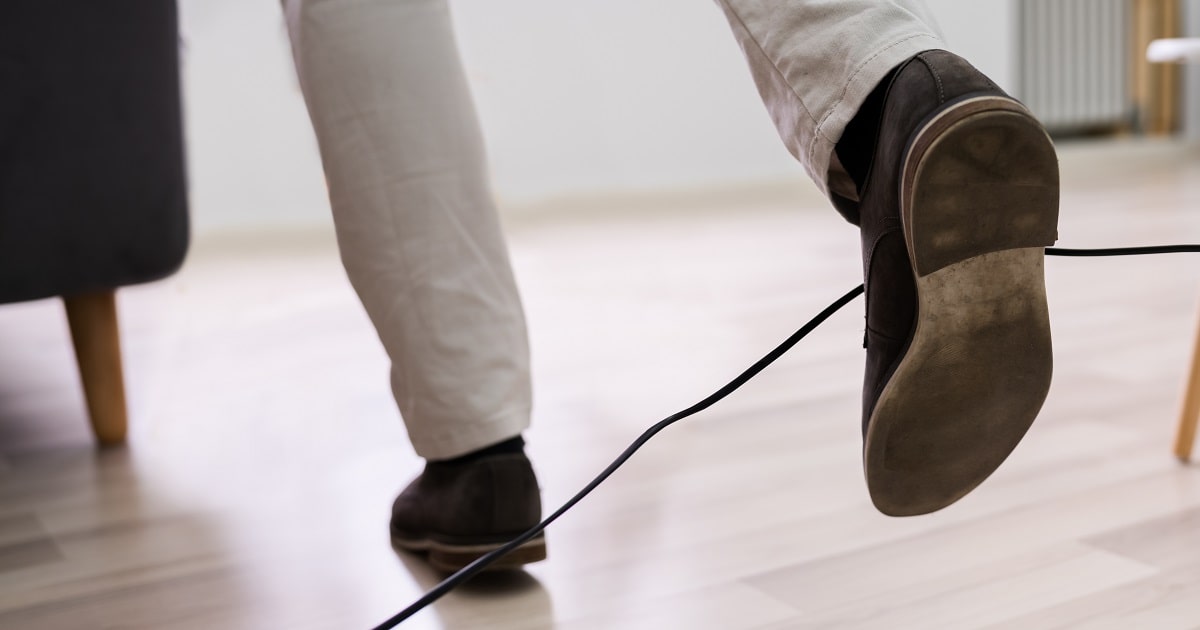 ケーブルに足を引っかけて、PCが落ちそうになっているビジネスパーソン