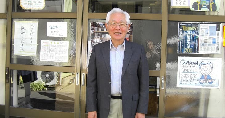 中村印刷所の外でにっこり微笑む中村社長