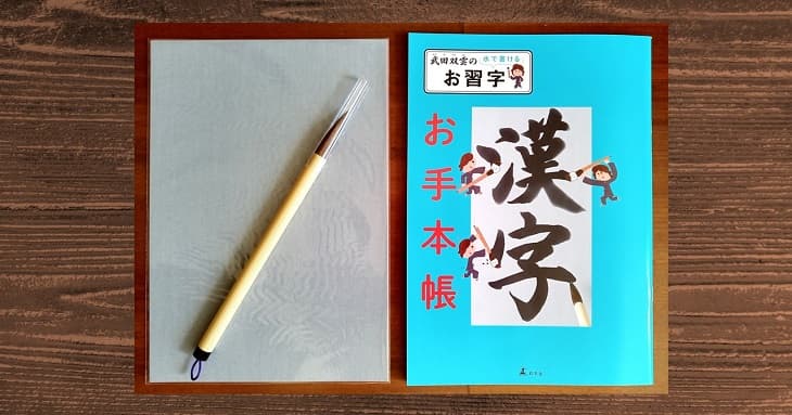 「武田双雲の水で書けるお習字 漢字」の中身。筆と用紙とお手本帳。