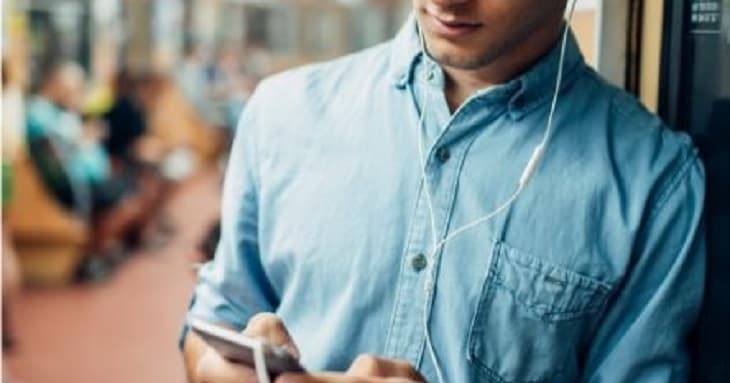 電車の移動時間にスマートフォンのアプリで勉強しようとしているビジネスパーソン