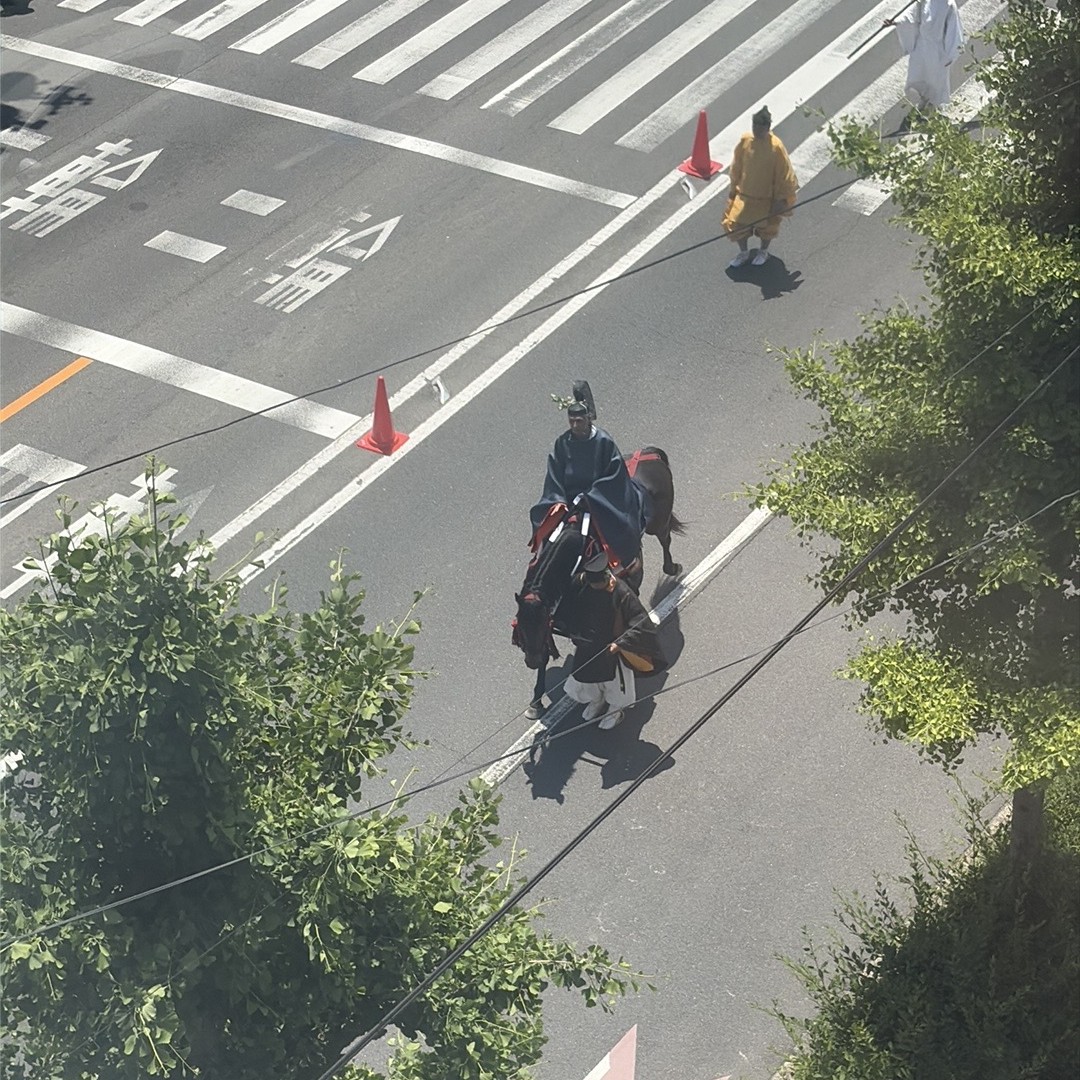 紫装束で黒毛の馬に乗る高貴な人物