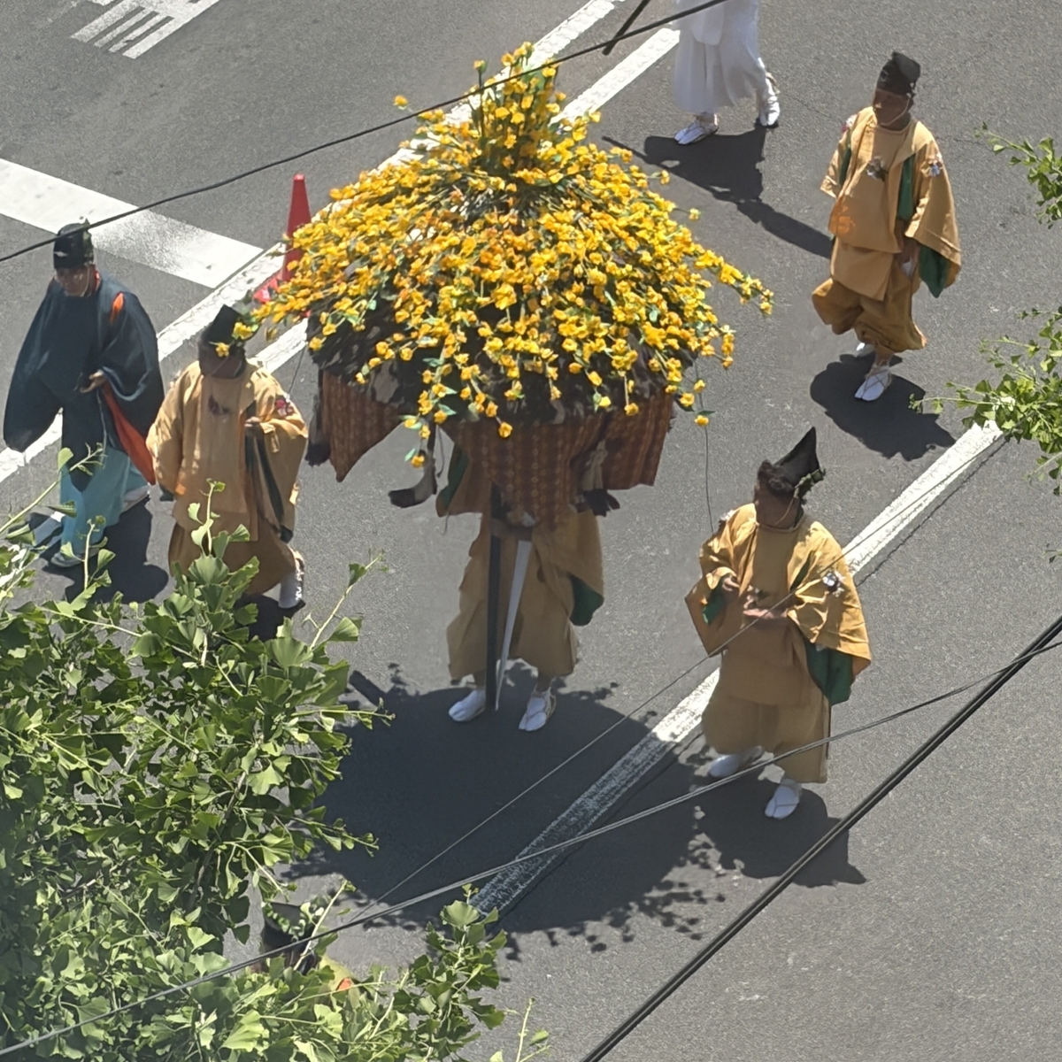 黄色い傘と薄黄色装束の付き人たち