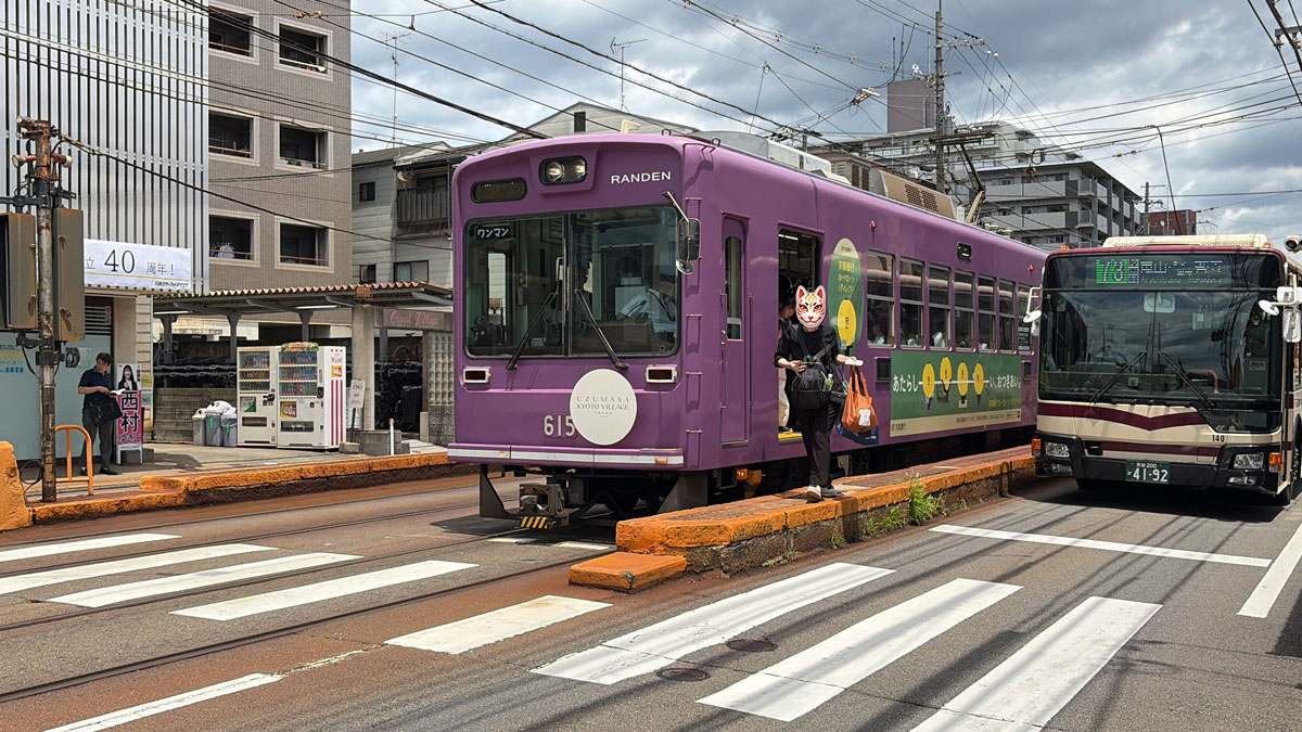 横断歩道を渡る乗客と停車する電車とバス