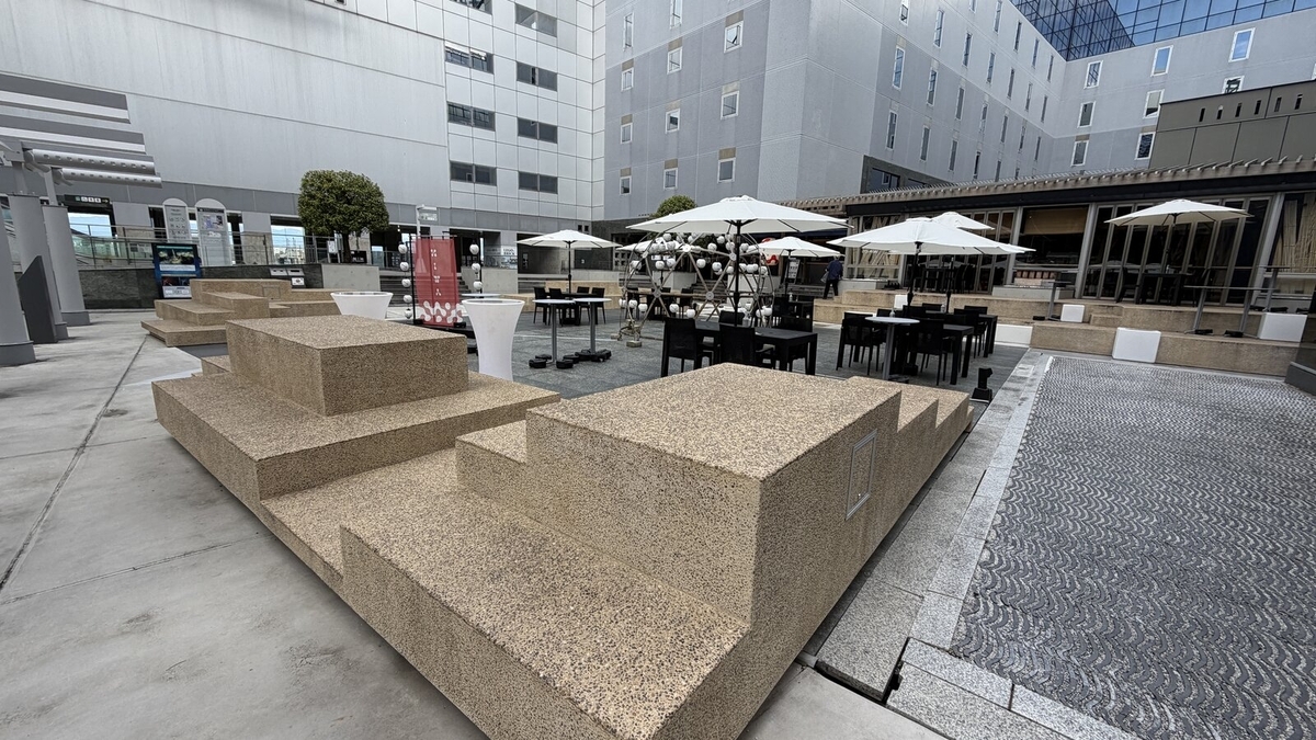 東広場にある石のベンチとカフェNIWAのパラソル席