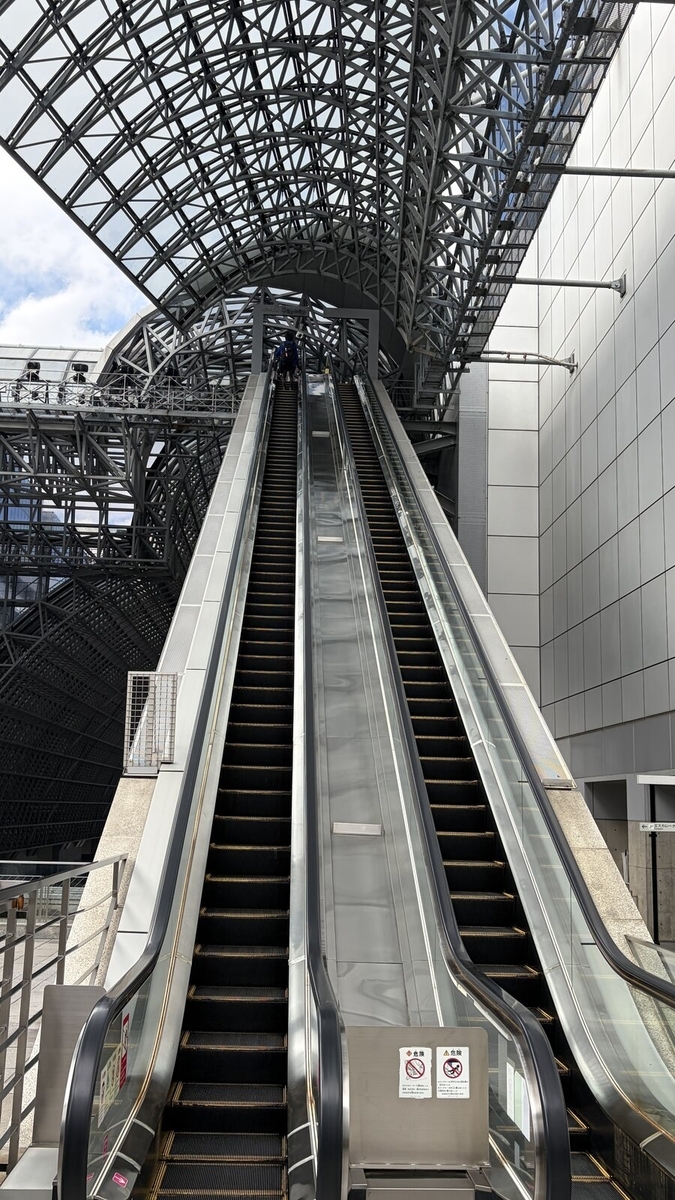 鉄骨の屋根へ向かって伸びる長いむき出しのエスカレーター