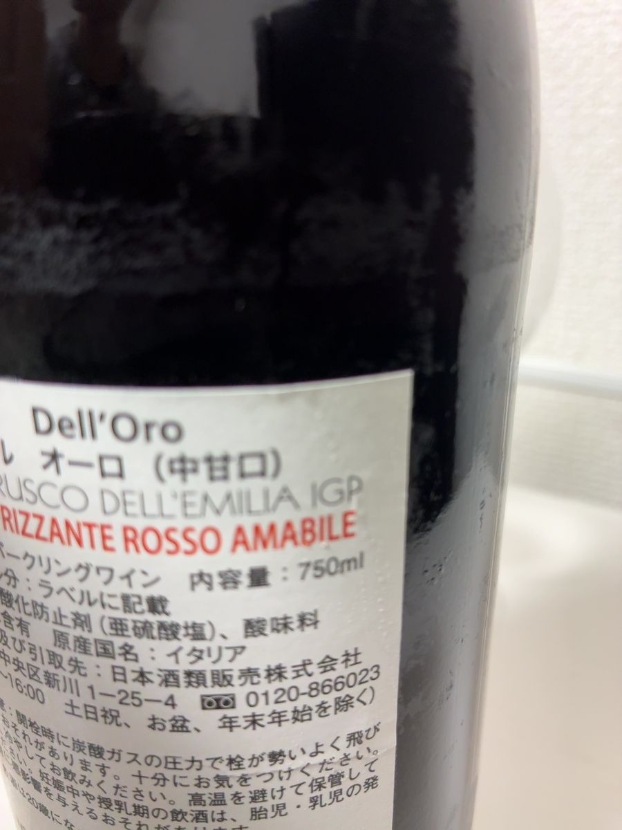ラベルには「Dell'Oro」と書かれており、その下に「レオーロ (中甘口)」と日本語で書かれています。さらに、「RUSCO DELL'EMILIA IGP RIZZANTE ROSSO AMABILE」という文字も見えます。これは、ワインの種類や産地を示しているようです。 内容量は「750ml」と記載されており、酸化防止剤として「亜硫酸塩」が使用されていること、そして酸味料が含まれていることも読み取れます。輸入元は「日本酒類販売株式会社」で、住所は「中央区新川1-25-4」です。電話番号は「0120-866023」と書かれています。 原産国は「イタリア」であることが明記されています。また、開栓時の注意点として、炭酸ガスの圧力で栓が勢いよく飛び出す可能性があること、高温を避けて保管すること、妊娠中や授乳期の飲酒は胎児や乳児に悪影響を与える可能性があることなどが注意喚起されています。