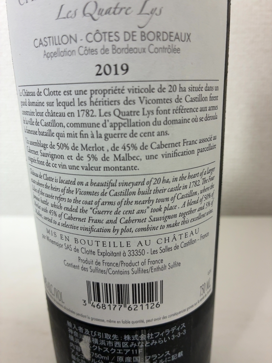 シャトー・ド・クロット レ・キャトル・リの裏ラベル。白地に黒文字で「Les Quatre Lys」「CASTILLON · CÔTES DE BORDEAUX」「2019」の表記。フランス語と英語で生産者・キュヴェ名の由来が印刷されている。下部にバーコードと750MLの表示。