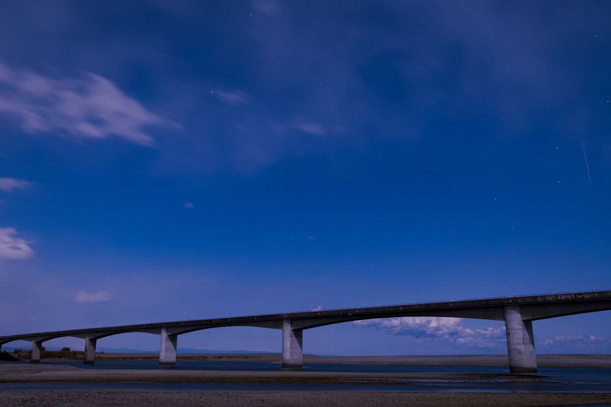 橋の上、右手にうす雲越しの流星。