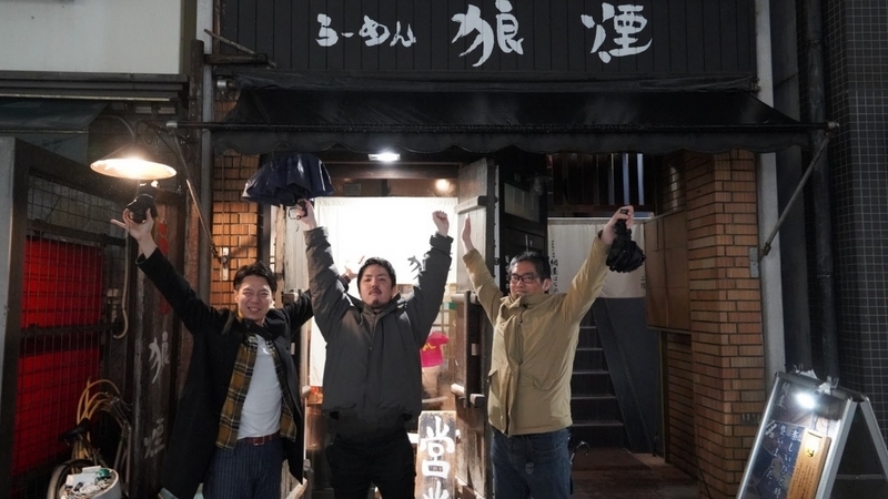 ラーメン屋狼煙の前で10店舗完遂の喜びを表す3人
