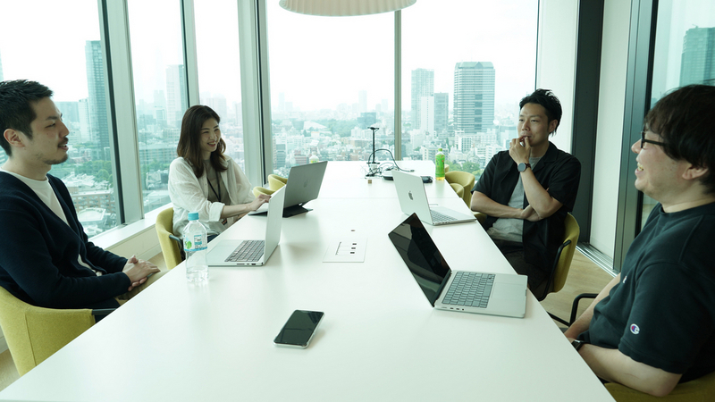 SmartHRオフィスのミーティングルームでEM山本、CEO芹澤の向かいにVPoE森住、PO塚本が座って談笑している