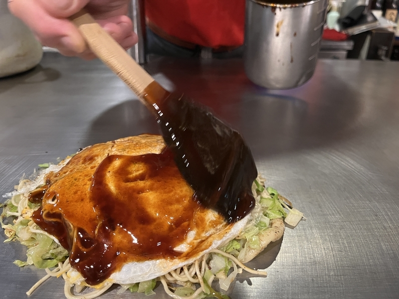 お好み焼きにソースを塗ってもらう