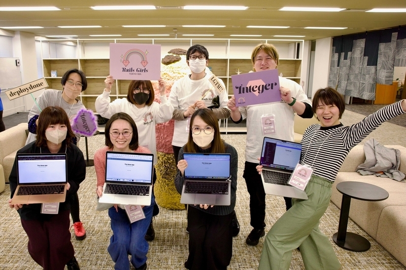 Integerチームの集合写真8名の男女。前列の4名の女性が作ったアプリをラップトップで表示してこちらに見せている。楽しそう！