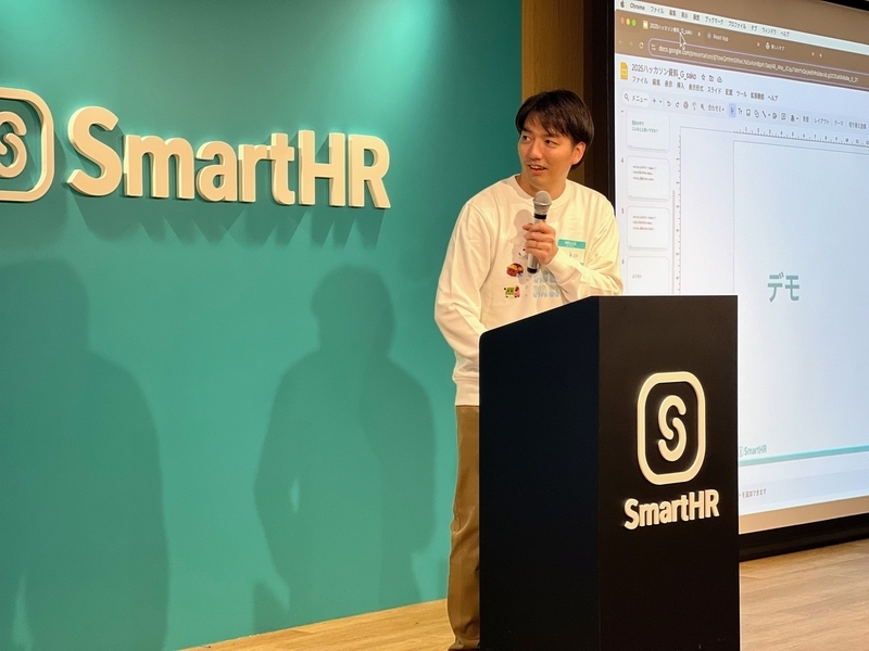 スクリーンを見ながらプレゼンテーションを行っている