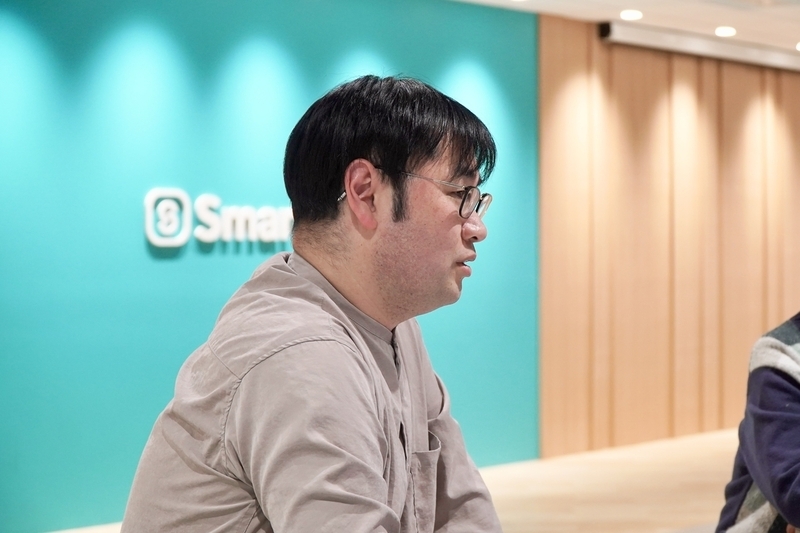 真剣な表情で話すwattunさん。背景にはSmartHRロゴを掲示した壁